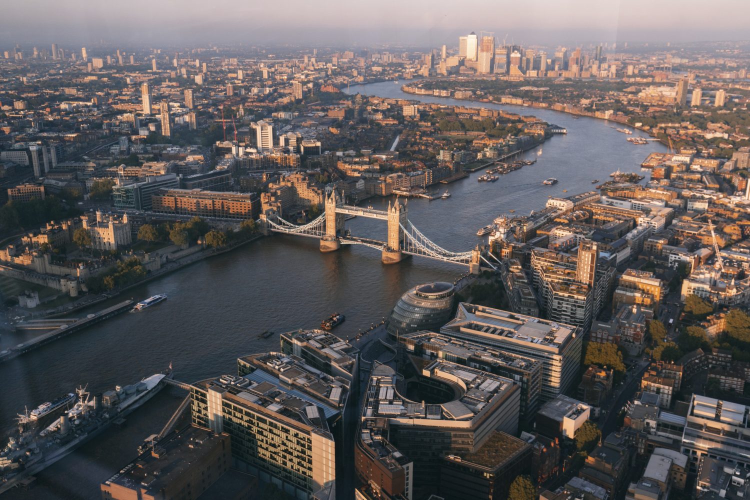 Aerial view of central London with the River Thames and Tower Bridge amid a dense city skyline.
