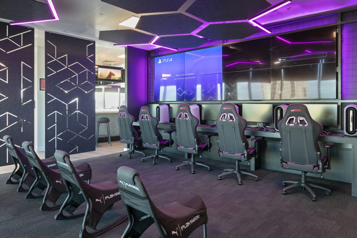 Interactive gaming centre in the London office with gaming chairs and large wall of screens/monitors.