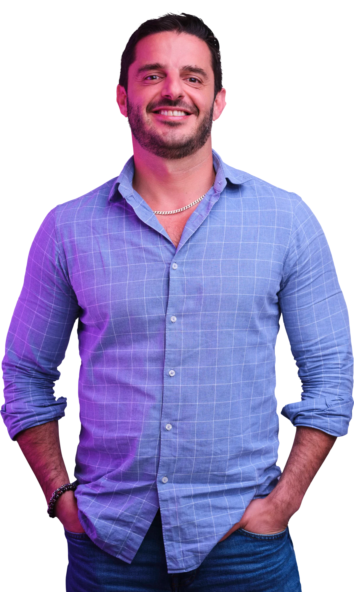 Smiling man in a light blue plaid button-up shirt with rolled-up sleeves and hands in his pockets.