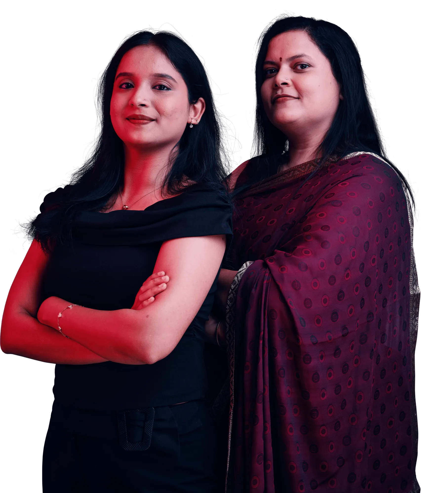 Two women stand side by side with arms crossed, one wearing a black dress and the other in a maroon sari.
