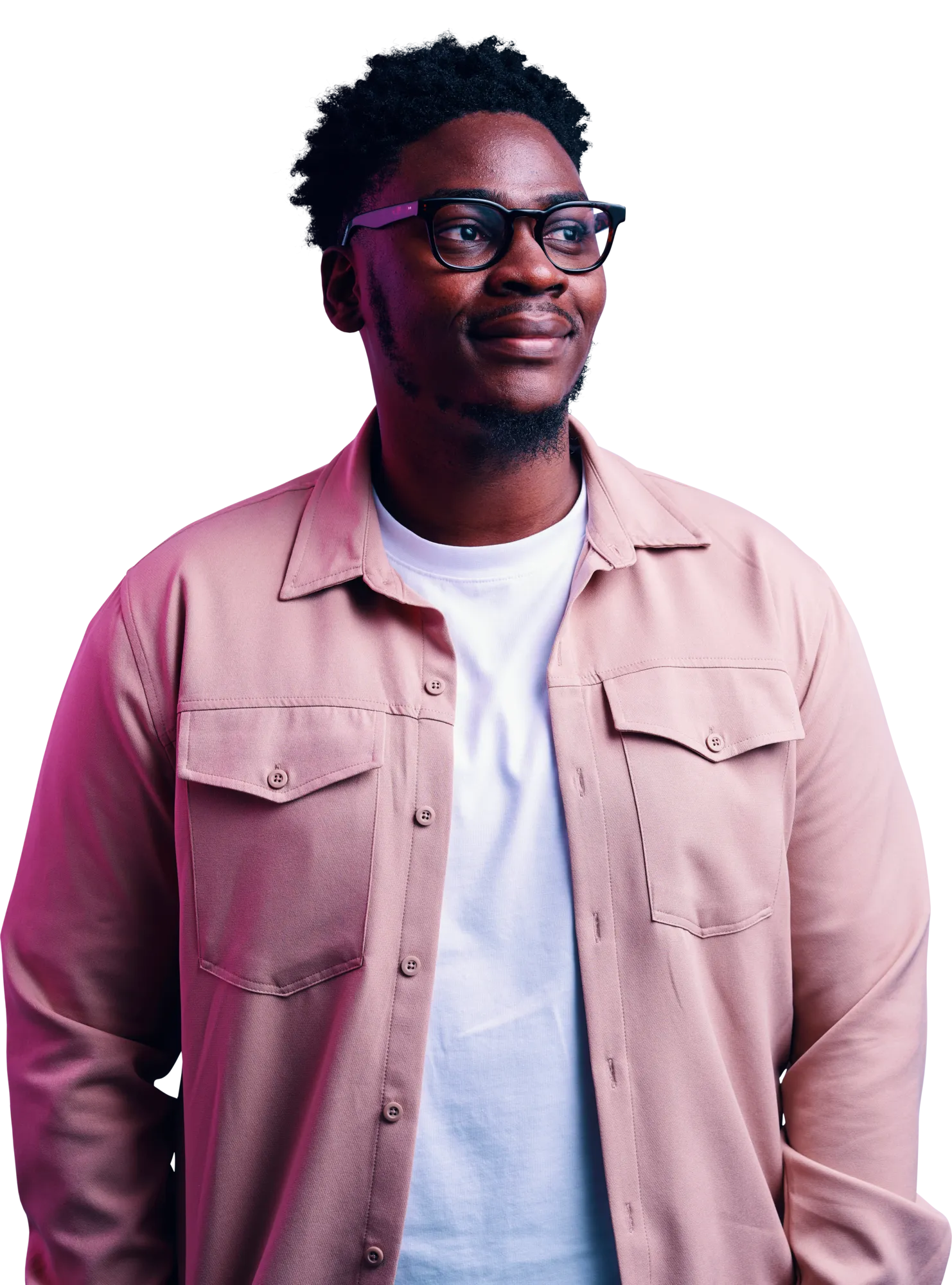 A man with glasses wearing a light pink button-up shirt over a white T-shirt, standing against a dark background.