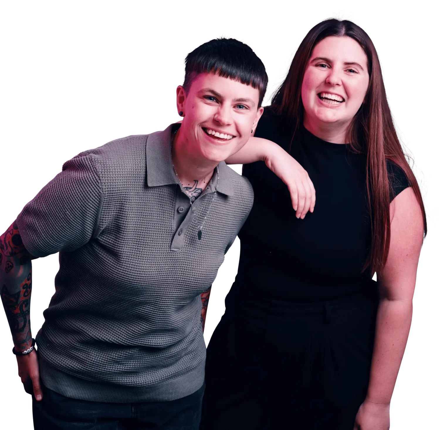 Two smiling friends pose together with one arm around the other; one wears a gray polo shirt and the other a black dress.