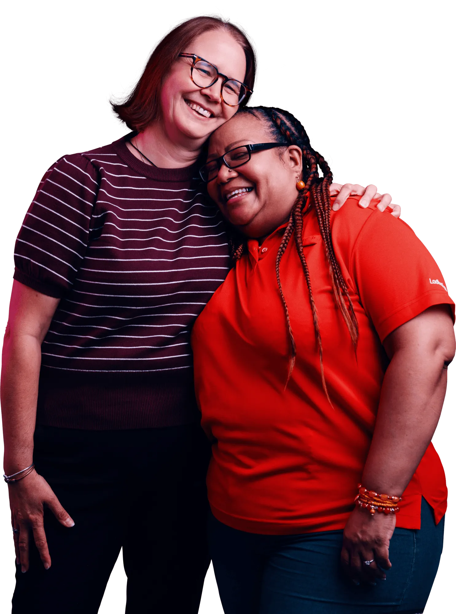 Two women stand close together with their arms around each other, smiling at the camera.