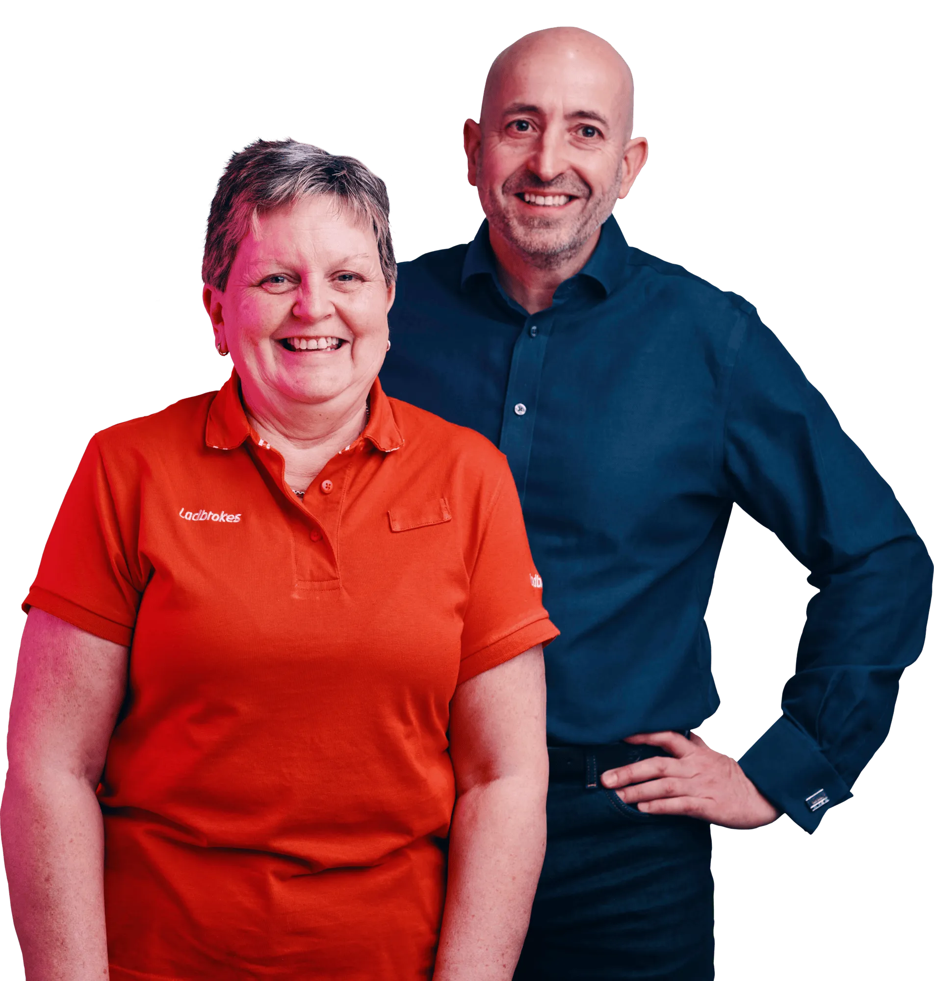Two smiling adults stand together, a woman in an orange polo shirt and a bald man in a dark blue shirt.