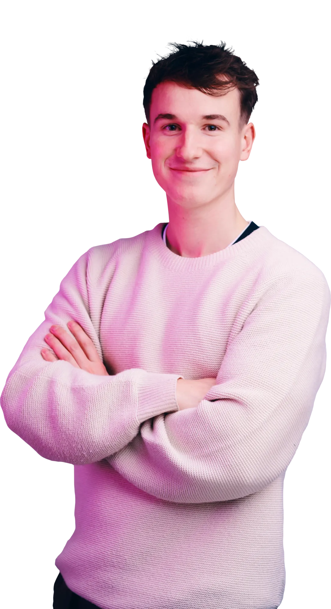 A young man with short dark hair wearing a pink sweater stands with his arms crossed and a slight smile.
