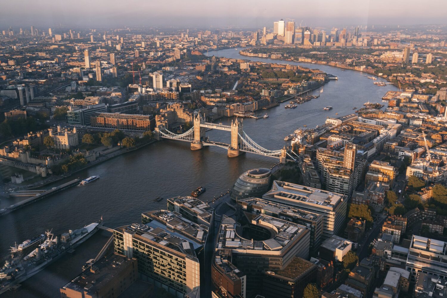 Aerial view of a dense city with a winding river and a large bridge spanning the water.