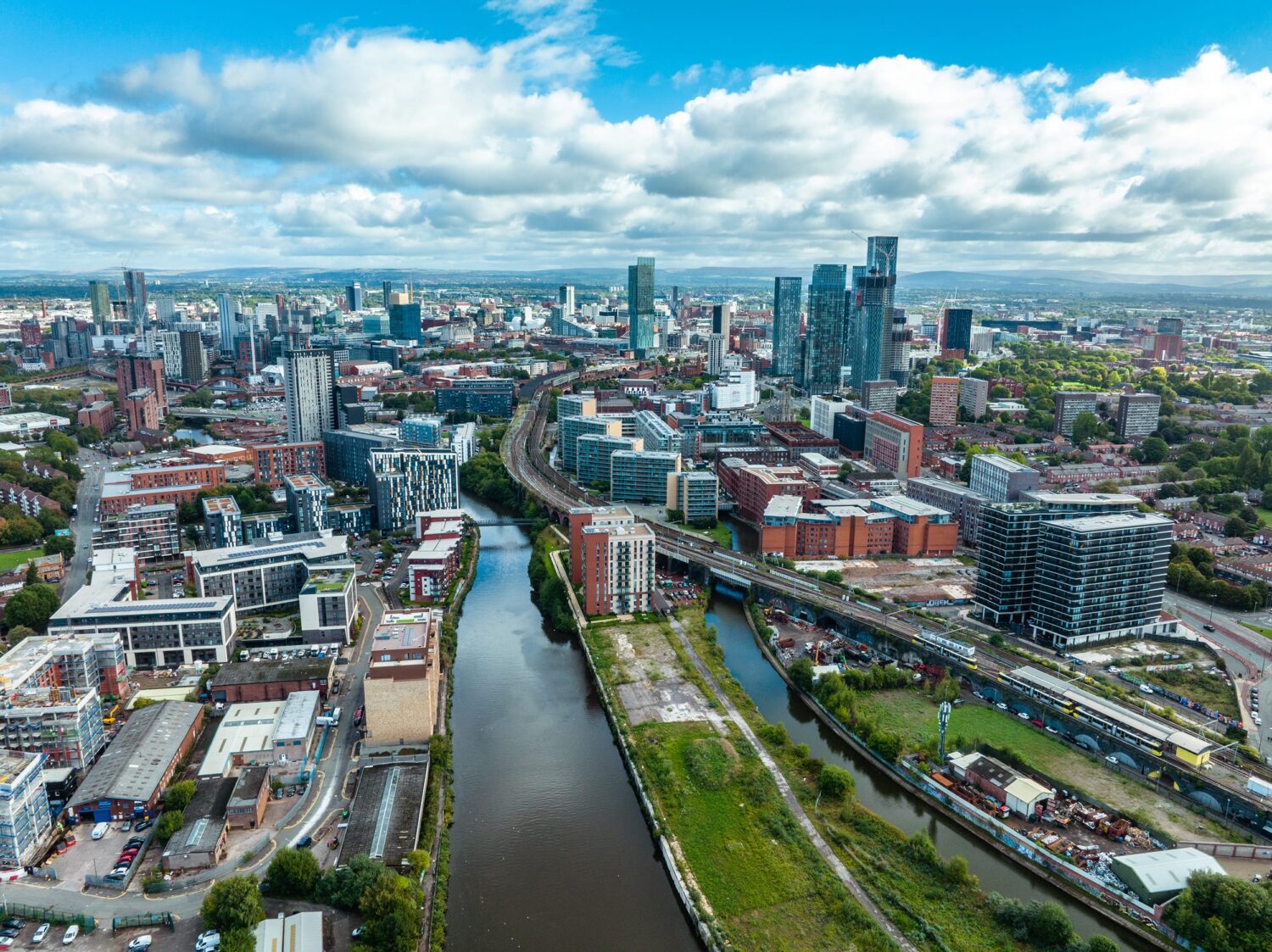 Aerial view of a city with a winding river, multiple bridges, and a mix of modern high-rise and low-rise buildings.
