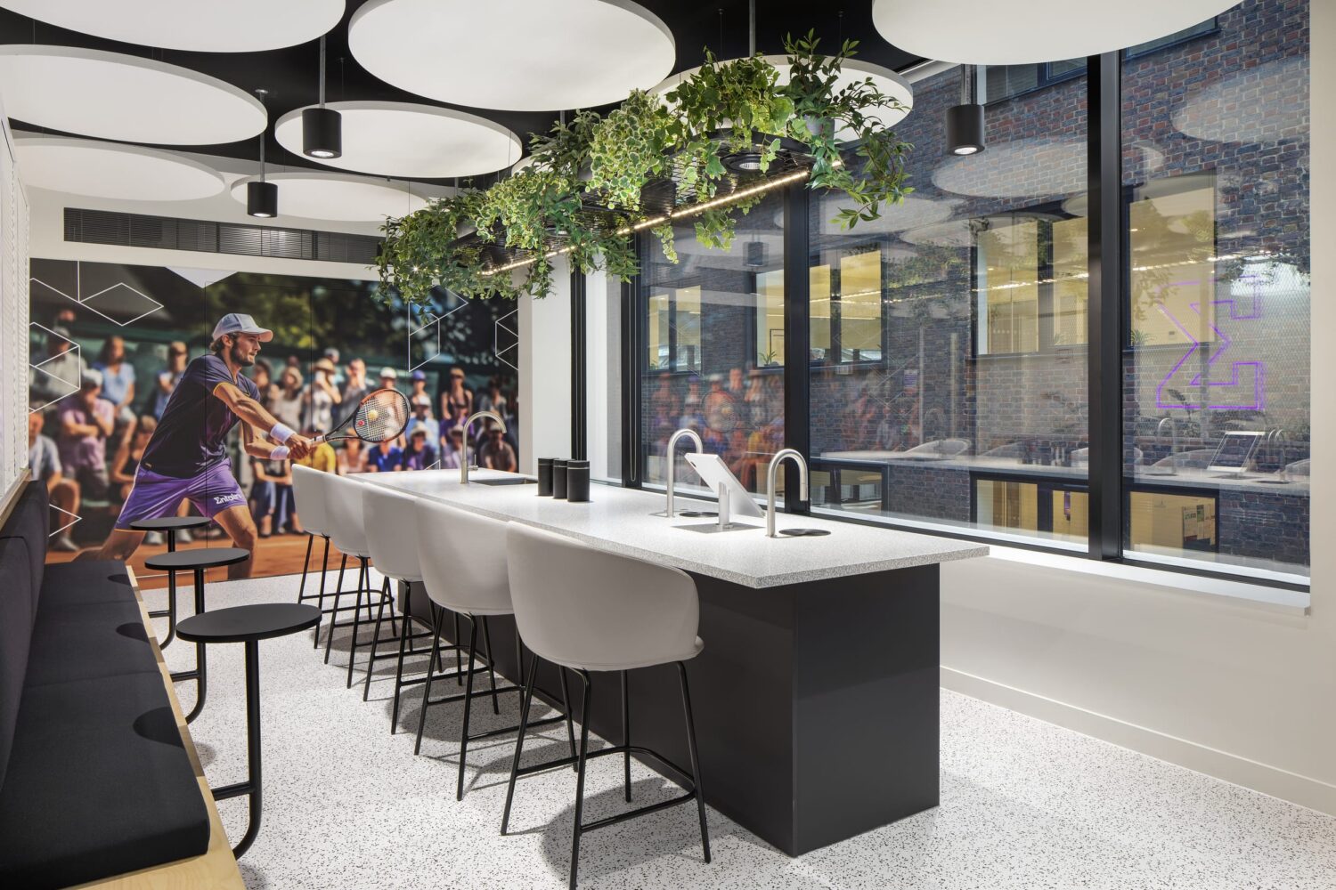 Shot of an office set up with a large table and stools, and a print of a tennis player on the wall.