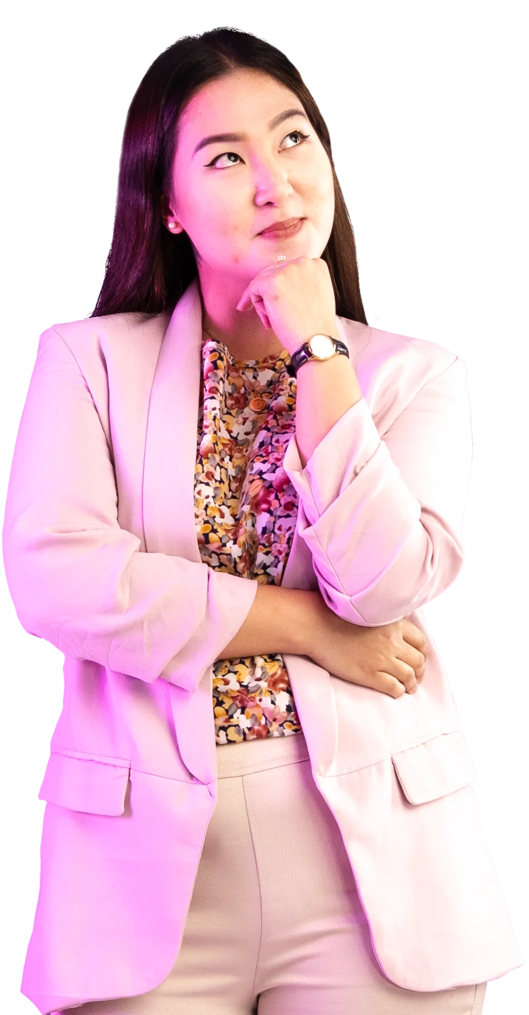 Woman wearing a pink blazer and floral blouse stands with her hand on her chin in a thoughtful pose.